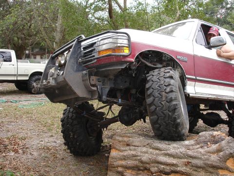 1989 Ford Bronco - This lifted 1989 Ford Bronco is positioned on a rock, its large off-road tires and modified suspension.
