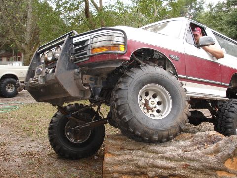 1989 Ford Bronco - Modified 1989 Ford Bronco tackling an off-road obstacle. A second vehicle is in the background.