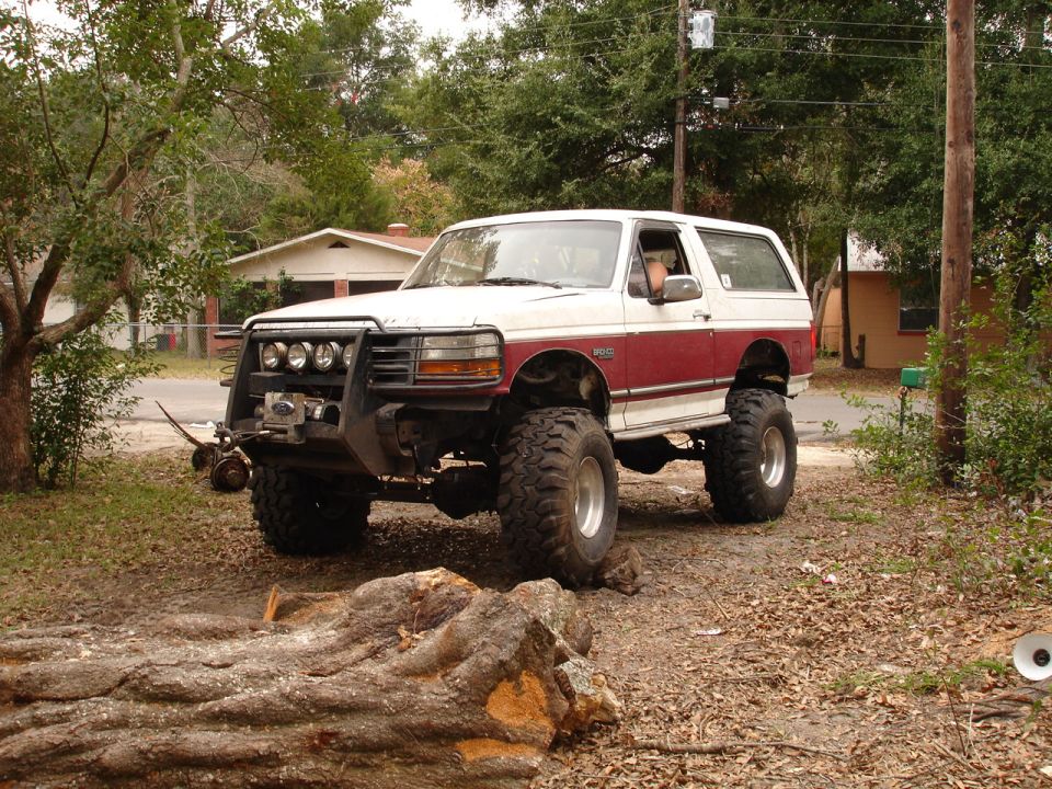 White and red lifted Ford Bronco with brush guard and winch