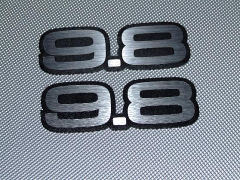 1990 Ford Mustang - Two "9.8" emblems are shown against a textured gray background.