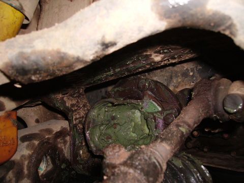 2000 Chevrolet Tahoe - A close-up view of a heavily greased suspension component, possibly a ball joint, with a yellow tag visible.