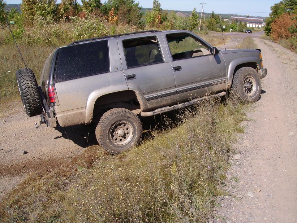 Silver SUV on dirt road, spare tire mounted on rear bumper. Appears to be a 1995 model