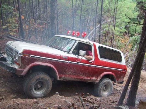 1995 Ford Bronco - This two-tone Ford Bronco navigates a muddy, wooded trail with auxiliary lights mounted on its roof.