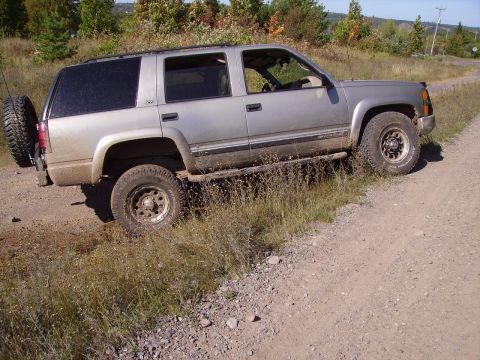 2000 Chevrolet Tahoe - Silver 2000 Chevrolet Tahoe on a dirt road with vegetation.