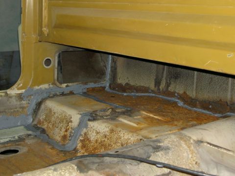 1967 Ford Ranchero - Close-up of the interior floor pan, showing areas of rust and recent sealant application.