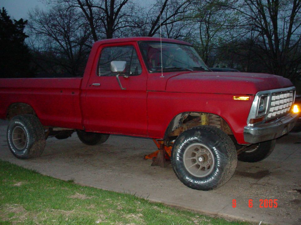 Red pickup truck with BFGoodrich tires, jacked up on the front right side