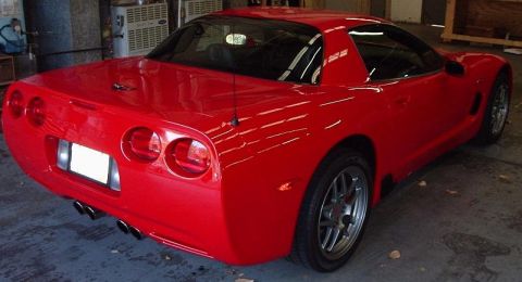 2002 Ford F-150 - This red sports car features a distinctive C5 Corvette body style with quad exhaust pipes visible from the rear.