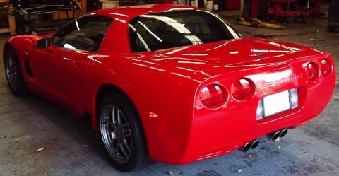 2002 Ford F-150 - Red Corvette C5 with quad exhaust pipes and "CORVETTE" badging visible on the rear.