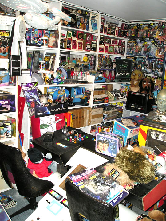 Room filled with Star Trek toys, models, and memorabilia on shelves and tables