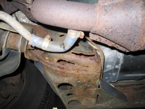 1991 Ford LTD Crown Victoria - Severe rust damage is visible on the vehicle's frame and exhaust system.