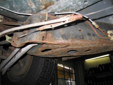 1991 Ford LTD Crown Victoria - The underside of the vehicle displays extensive rust damage, particularly on the frame and suspension parts.