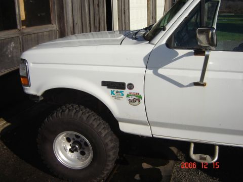 1993 Ford Bronco - Close-up of a white 1993 Ford Bronco fender, showing the 'Bronco' badge and various stickers.
