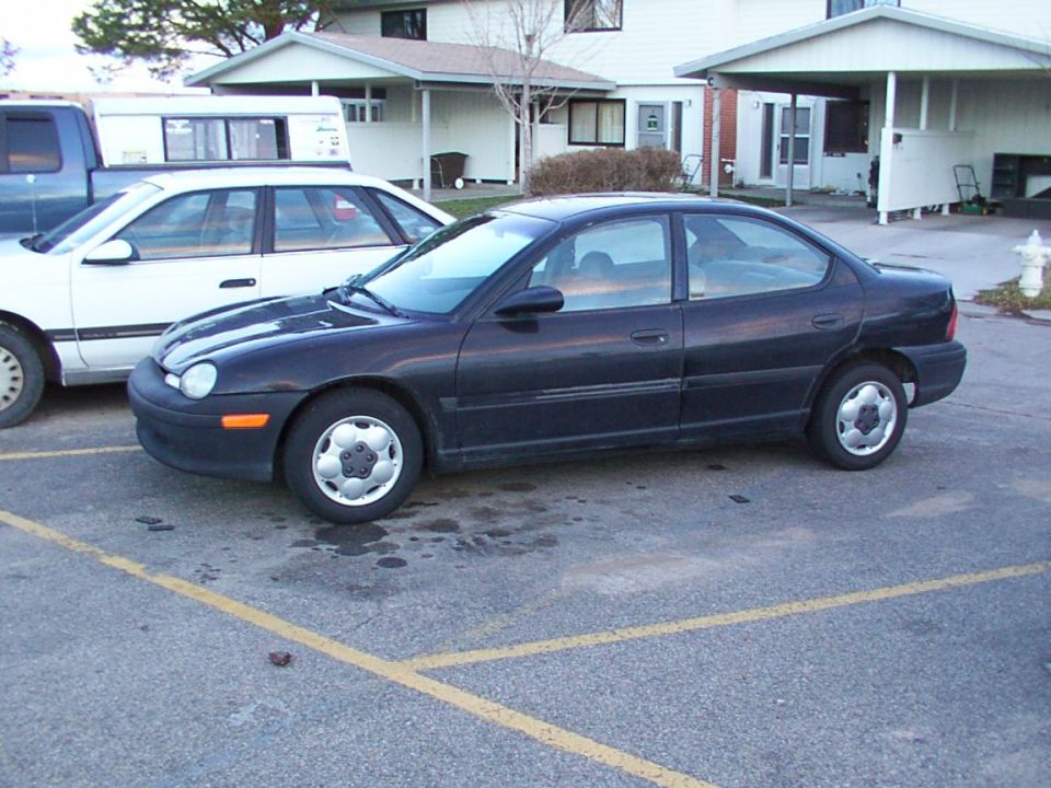 Dark sedan parked next to a white car and a blue truck
