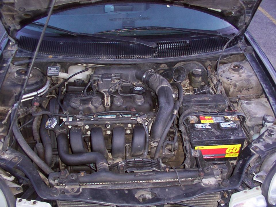 engine bay with battery and hoses visible
