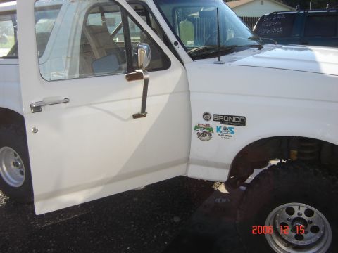 1993 Ford Bronco - White 1993 Ford Bronco with door open, 'BRONCO CUSTOM' and other stickers on the fender.