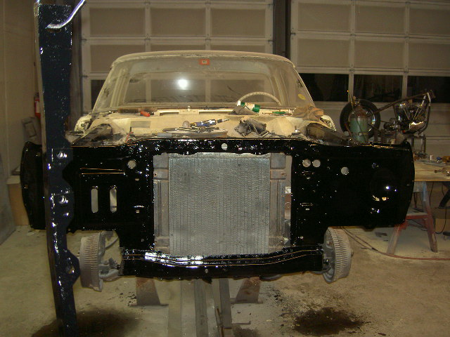 Car front end on lift, radiator exposed, black painted fenders