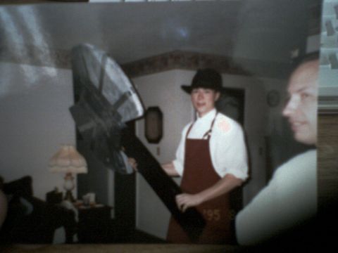 2001 Ford Crown Victoria - A person dressed in a hat and apron holds a large, dark object in what appears to be a residential setting.