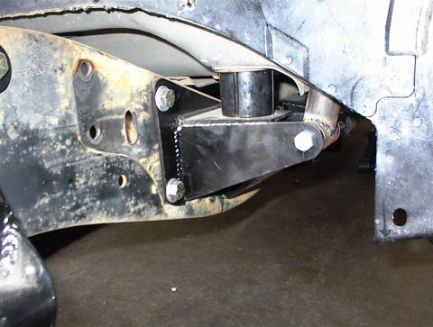1984 Ford Bronco - Aftermarket suspension bracket installed on a vehicle frame, showing bolted connections and a rubber bushing.