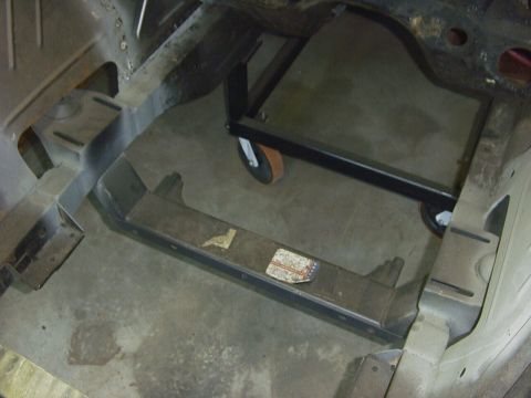 1990 Ford Mustang - The underside of a vehicle's frame is shown, with a dolly supporting part of the structure.