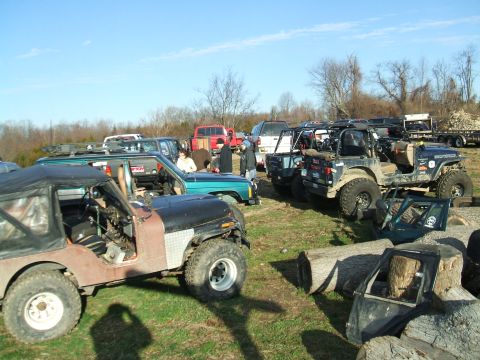1995 Ford Bronco - A collection of off-road vehicles gathered in an open field on a sunny day.
