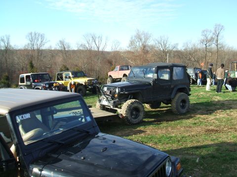 1995 Ford Bronco - A group of off-road vehicles are gathered in an open field on a sunny day.