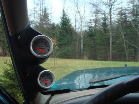 1996 Ford Bronco - Two aftermarket gauges are mounted on the A-pillar inside a vehicle, showing voltage and oil pressure readings.