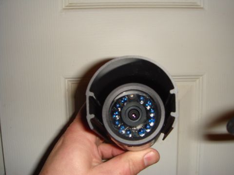 1996 Ford Bronco - A hand holds a security camera with blue LEDs surrounding the lens, in front of a white door.