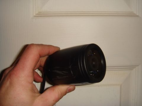 1996 Ford Bronco - A person holds a black security camera, with its lens visible, against a white paneled door.