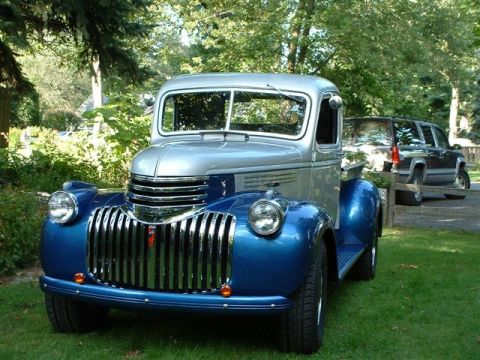 1946 Chevrolet C/K Pickup - Front view of a two-tone blue and silver 1946 Chevrolet C/K Pickup, with a modern SUV behind it.
