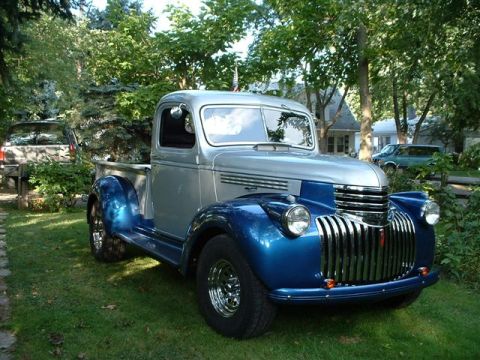 1946 Chevrolet C/K Pickup - A two-tone 1941 Chevrolet pickup truck is parked in a yard with other vehicles visible in the background.