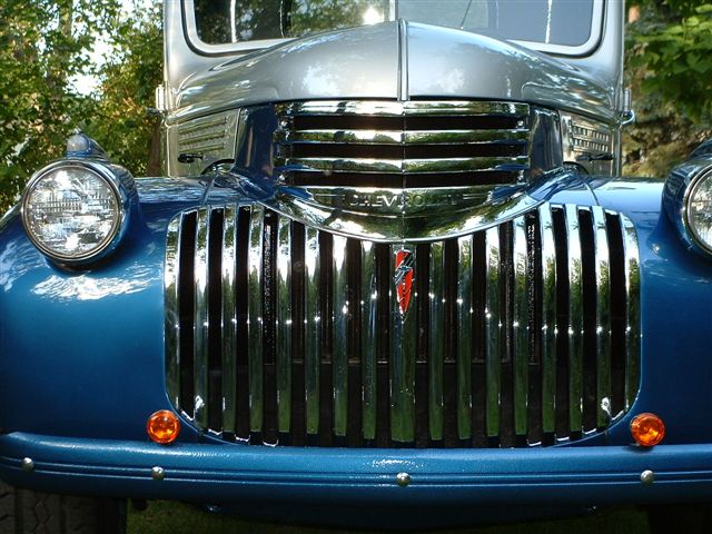 Blue Chevrolet pickup truck grille with chrome vertical bars and a red emblem