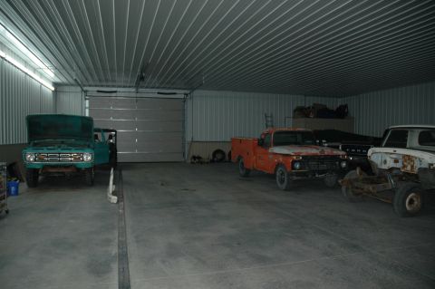 1963 Ford F-250 - A turquoise 1963 Ford F-250 is parked inside a garage with its hood open, alongside two other trucks.