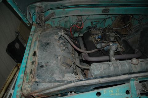 1963 Ford F-250 - The engine bay of a turquoise 1963 Ford F-250 shows signs of disassembly and wear.