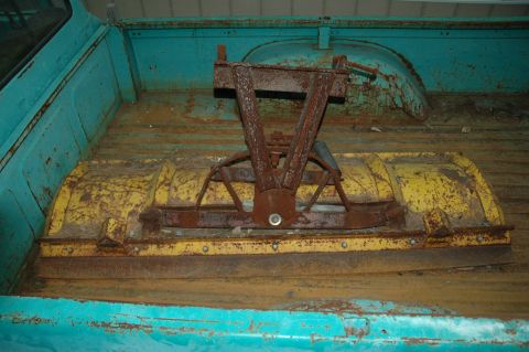1963 Ford F-250 - A rusty plow attachment is stored in the bed of a turquoise truck.