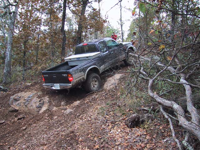 Pickup truck with a toolbox in the bed driving off-road on a wooded trail