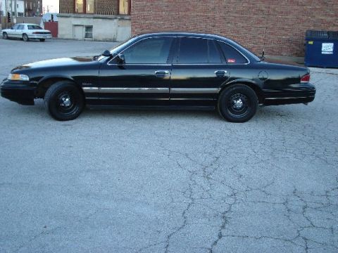 1992 Ford Crown Victoria - A black 1992 Ford Crown Victoria sedan is parked on asphalt, with another white car in the background.