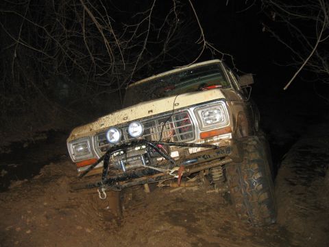 1992 Ford Mustang - Off-road Bronco stuck deep in mud, showing its winch and modified bumper.