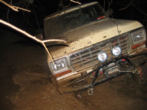 1992 Ford Mustang - This Ford truck is stuck deep in the mud, with branches overhead and auxiliary lights on the front.