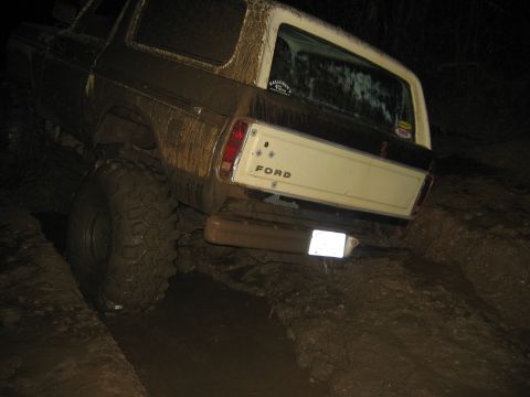 1992 Ford Mustang - This heavily muddied Ford Bronco is navigating a difficult off-road trail in the dark.