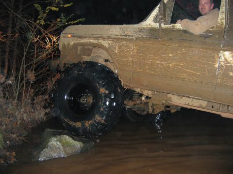 1992 Ford Mustang - A driver navigates a heavily muddied truck through a watery obstacle course at night.