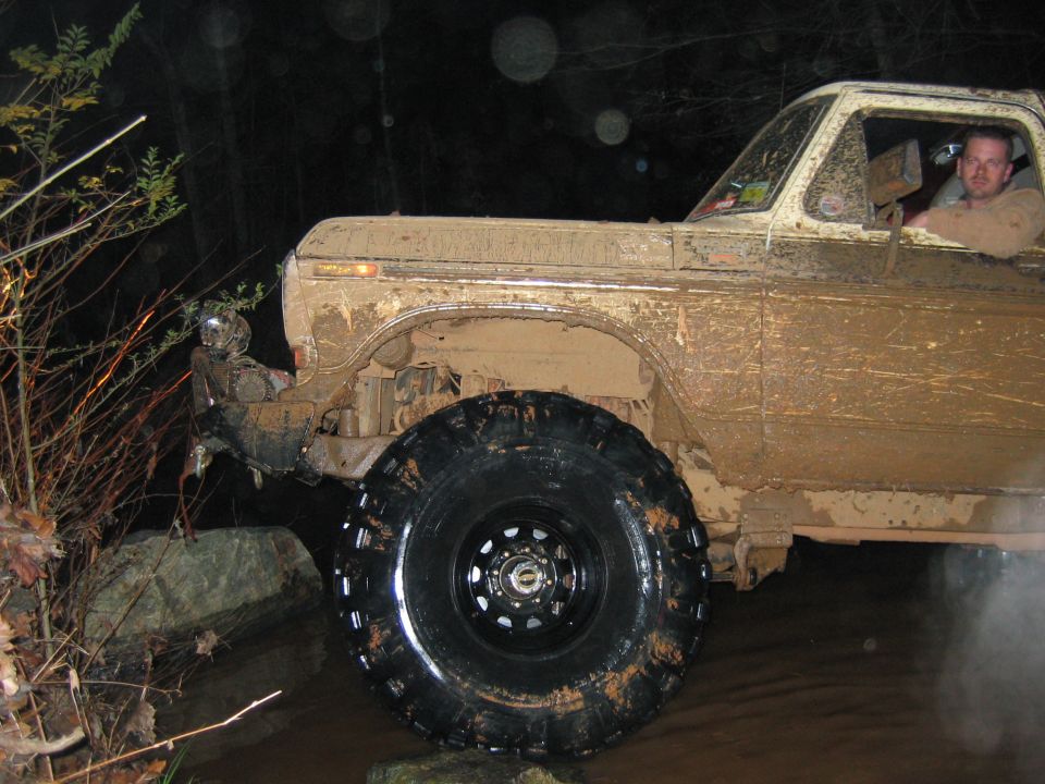 Mud-covered 1979 Ford F-Series pickup truck with large off-road tires navigating rough terrain