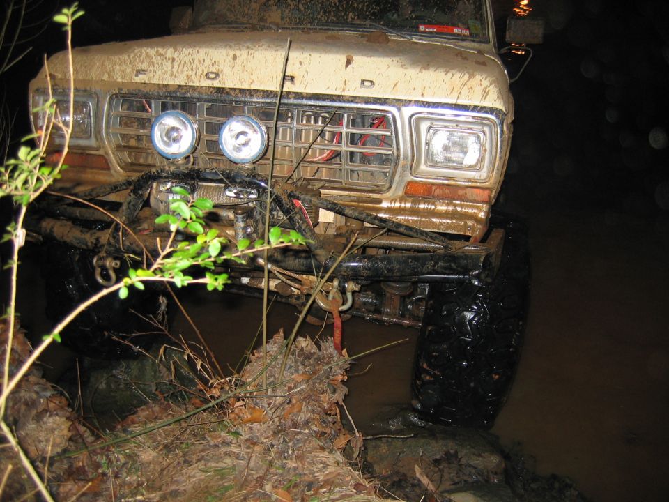 Front view of a muddy 1979 Ford F-Series truck with off-road lights and winch