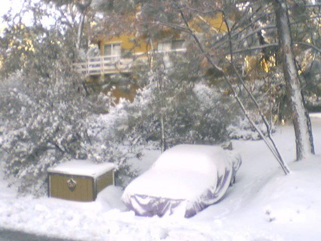car covered in snow next to a chest, house in background