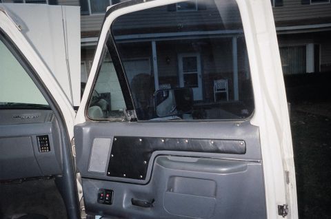1989 Ford Bronco - View of the driver's side door panel and dashboard of a white truck, with a house seen through the window.