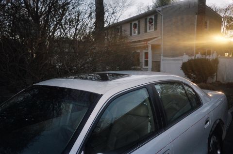 1989 Ford Bronco - A silver sedan is parked in front of a suburban house during sunset.