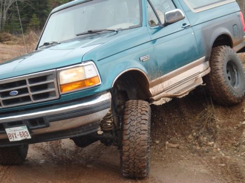 1996 Ford Bronco - Teal 1996 Ford Bronco with off-road tires navigating a dirt path.