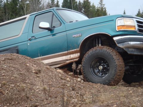 1996 Ford Bronco - This 1996 Ford Bronco is shown off-roading, climbing a dirt mound with its large tires.