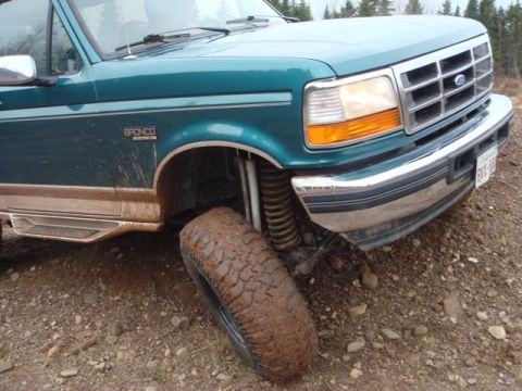 1996 Ford Bronco - Muddy 1996 Ford Bronco navigating rough terrain.