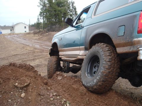 1996 Ford Bronco - This 1996 Ford Bronco is navigating a challenging muddy terrain with its off-road modifications.