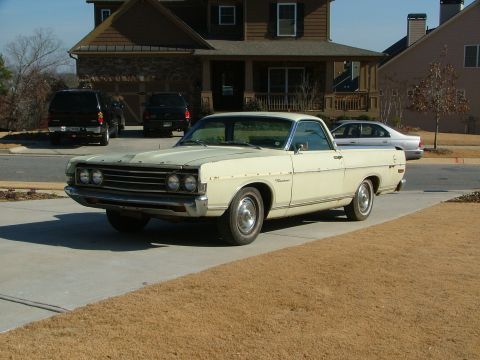 1969 Ford Ranchero - A cream-colored 1969 Ford Ranchero is parked in a suburban driveway with other vehicles present.